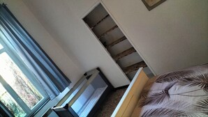 A bedroom with a bed, a window with curtains, a painting on the wall, and a staircase. - Pet-friendly apartment le petit paradis :) (Saint-Pons-de-Thomières)