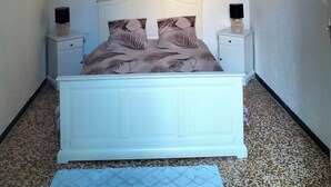 A bedroom with a white bed, two nightstands, and a door. - Pet-friendly apartment le petit paradis :) (Saint-Pons-de-Thomières)