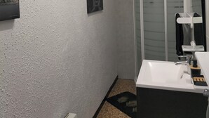 A bathroom with a white sink, a glass shower enclosure, a Buddha painting on the wall, and a textured ceiling. - Pet-friendly apartment le petit paradis :) (Saint-Pons-de-Thomières)
