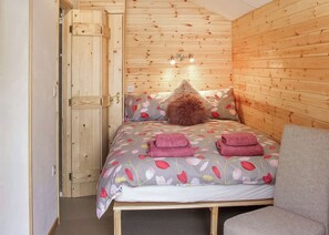 Une pièce en bois avec un lit, une chaise et une porte.