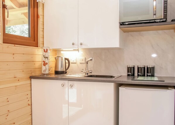 Une cuisine avec des murs en bois, une bouilloire en acier inoxydable, un four à micro-ondes et un évier.