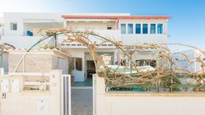 A two-story building with a white facade, a red roof, and a gate with a vine. - Cosy apartment for 5 people with A/C, WIFI, TV and veranda, close to Ostuni (Pantanagianni-pezze Morelli)
