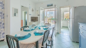 A dining area with a table set for four, chairs, a television, and a view of the outside. - Cosy apartment for 5 people with A/C, WIFI, TV and veranda, close to Ostuni (Pantanagianni-pezze Morelli)