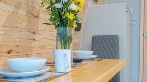 Une table de salle à manger en bois, avec des bols blancs, une tasse blanche et un vase rempli de fleurs.