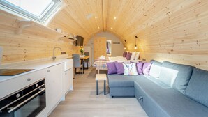 Un intérieur compact en bois comprenant une kitchenette, un coin repas et un canapé.