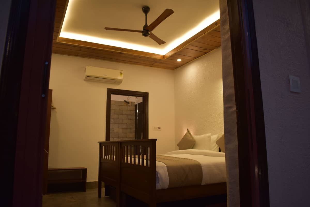 A bedroom with a wooden bed, a ceiling fan, and a wall-mounted air conditioner.