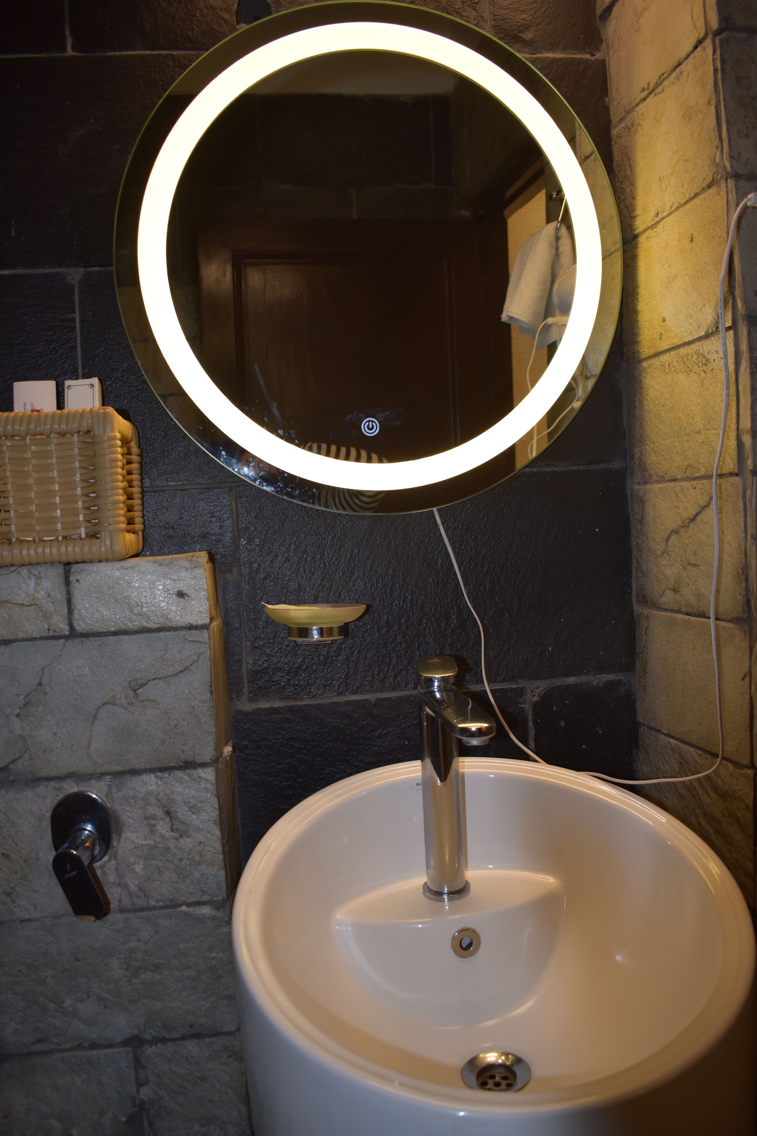 A bathroom with a round mirror, a sink, and a towel rack.