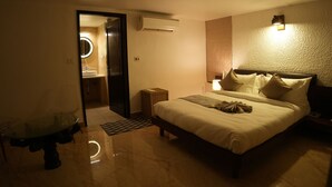 Una habitación de hotel con cama, mesita de noche, lámpara y unidad de aire acondicionado.