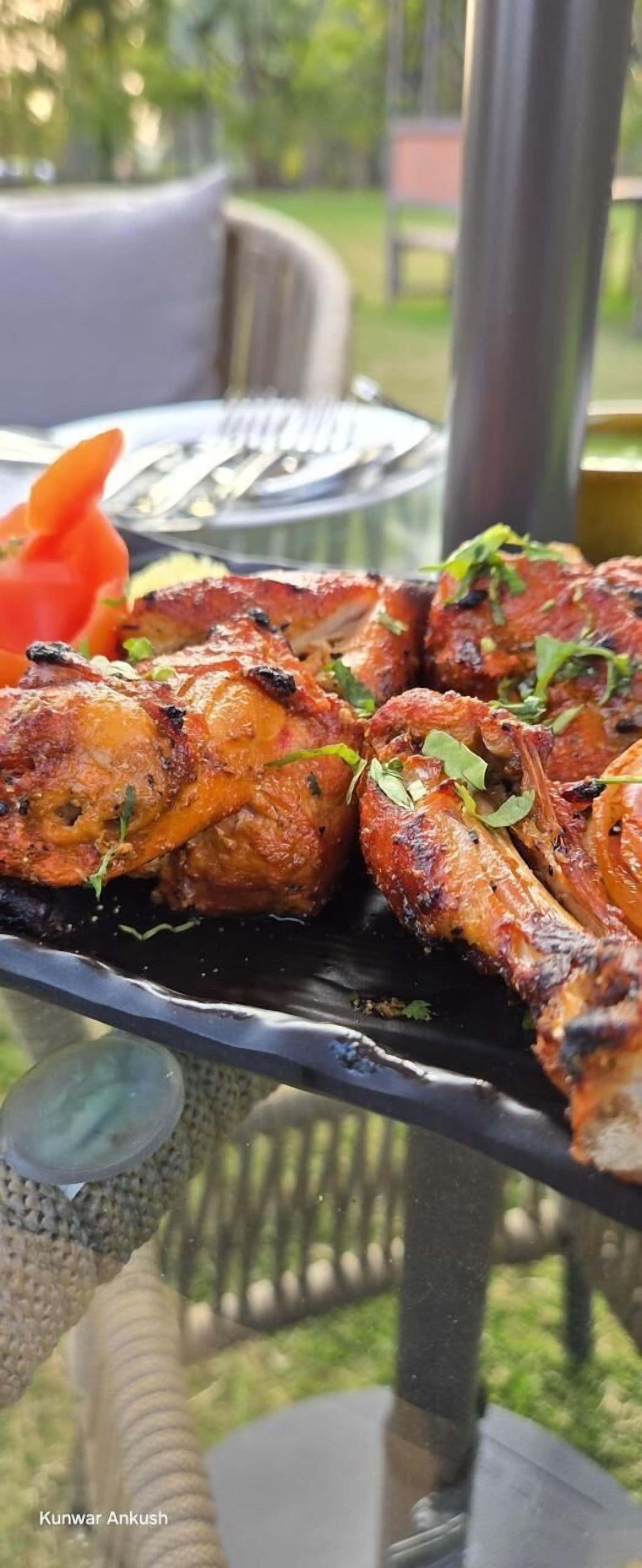 Une table en verre avec des ailes de poulet grillées et une portion de carottes en accompagnement.