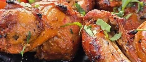 Une table en verre avec des ailes de poulet grillées et une portion de carottes en accompagnement.
