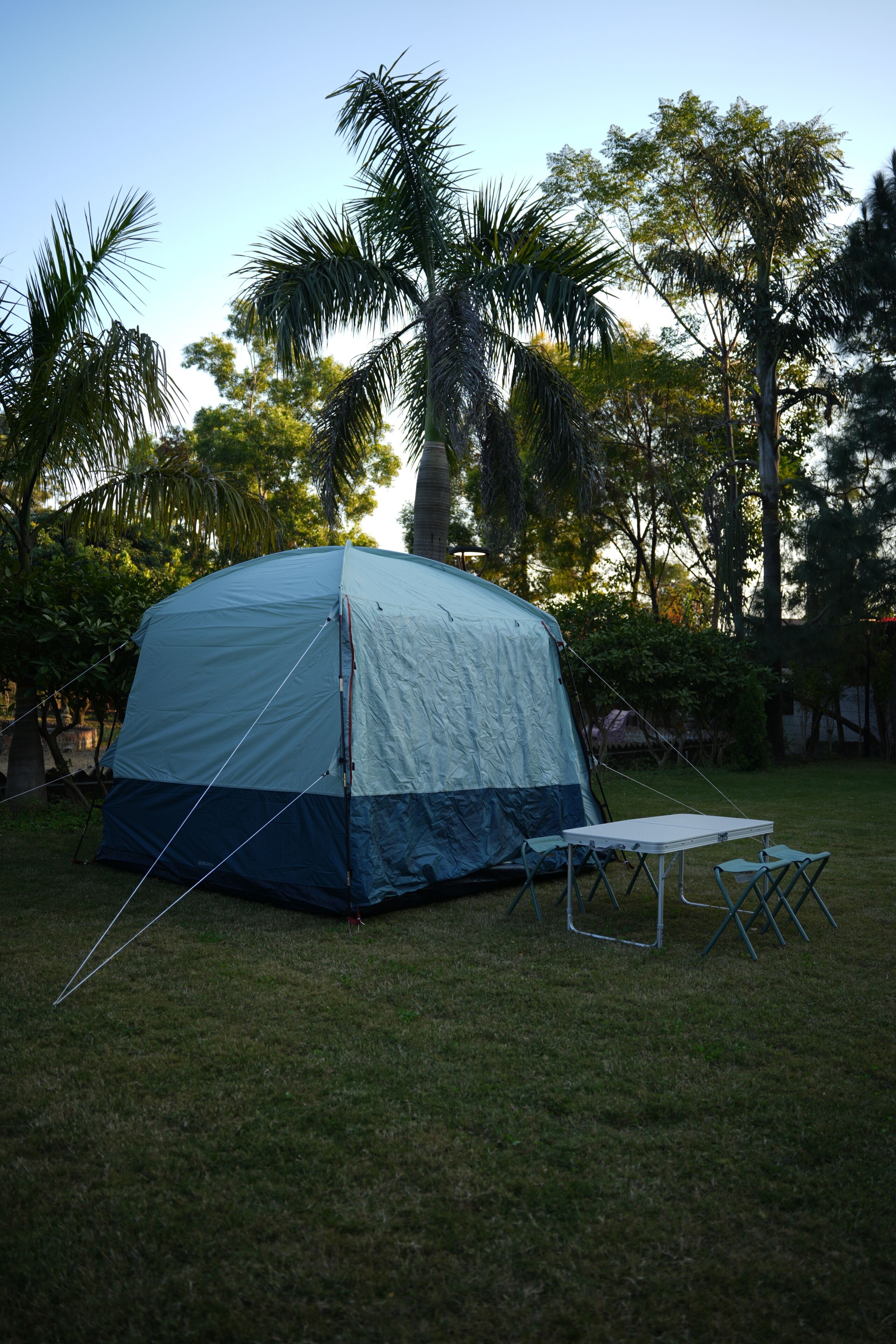 A tent set up in a grassy area with a table and chairs nearby.