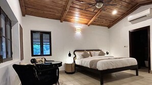 Un dormitorio con techo de madera, una cama, una mesita de noche, una silla y una ventana con vistas.