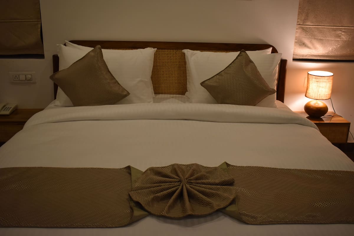 A neatly made bed with a large decorative pillow and a lamp on the side.