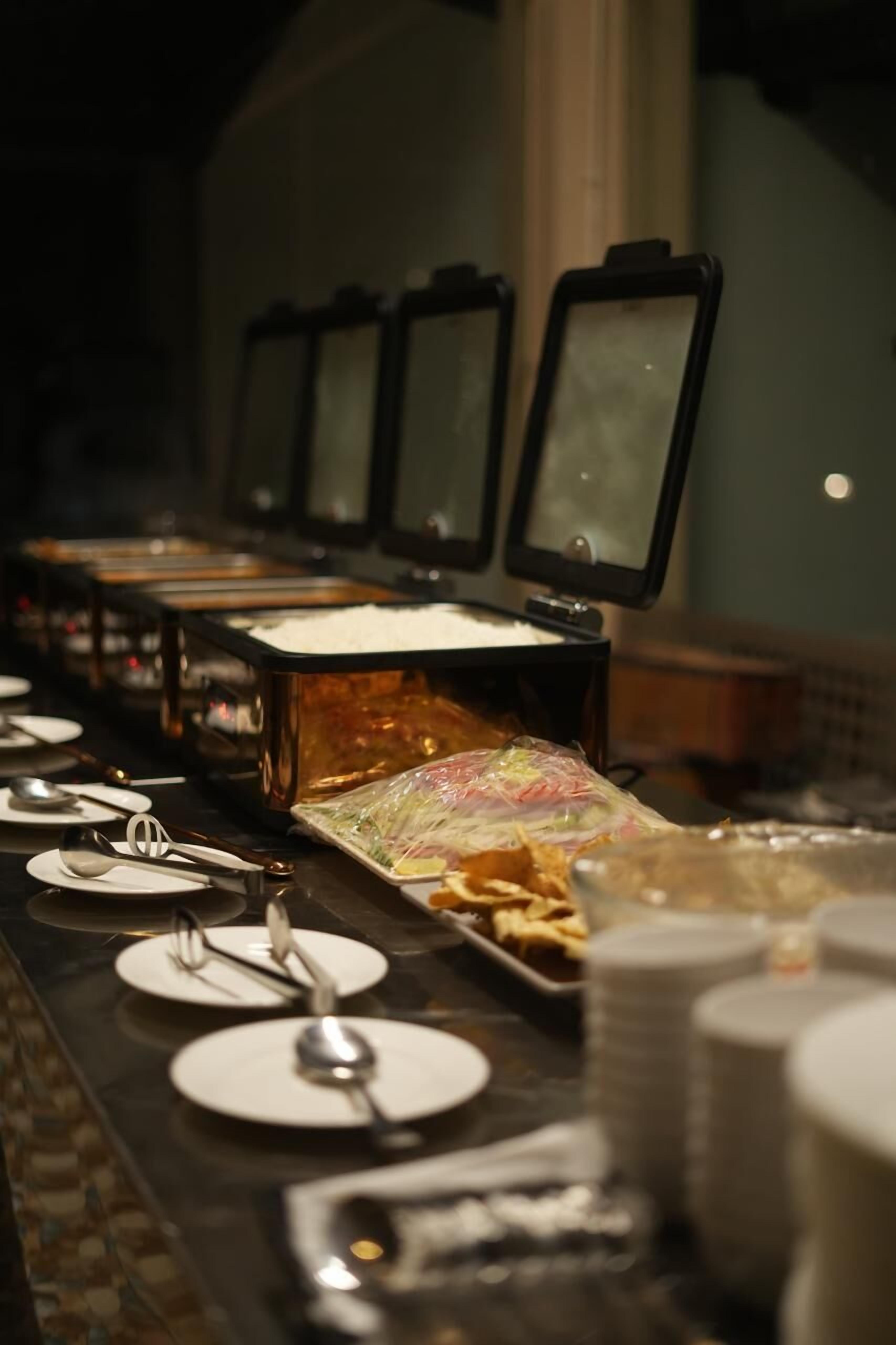Un buffet avec plusieurs points de service, des assiettes et des couverts à disposition.