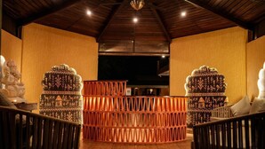 Una habitación con techo de madera y un separador central con diseños elaborados. Hay dos sillas a cada lado del separador.