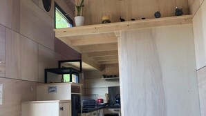 Een kleine keuken met houten kastjes, een inbouwoven en een klein aanrecht.