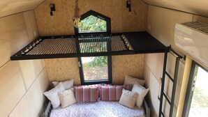 Een gezellige, compacte kamer met een bed, een raam en een klein tafeltje.