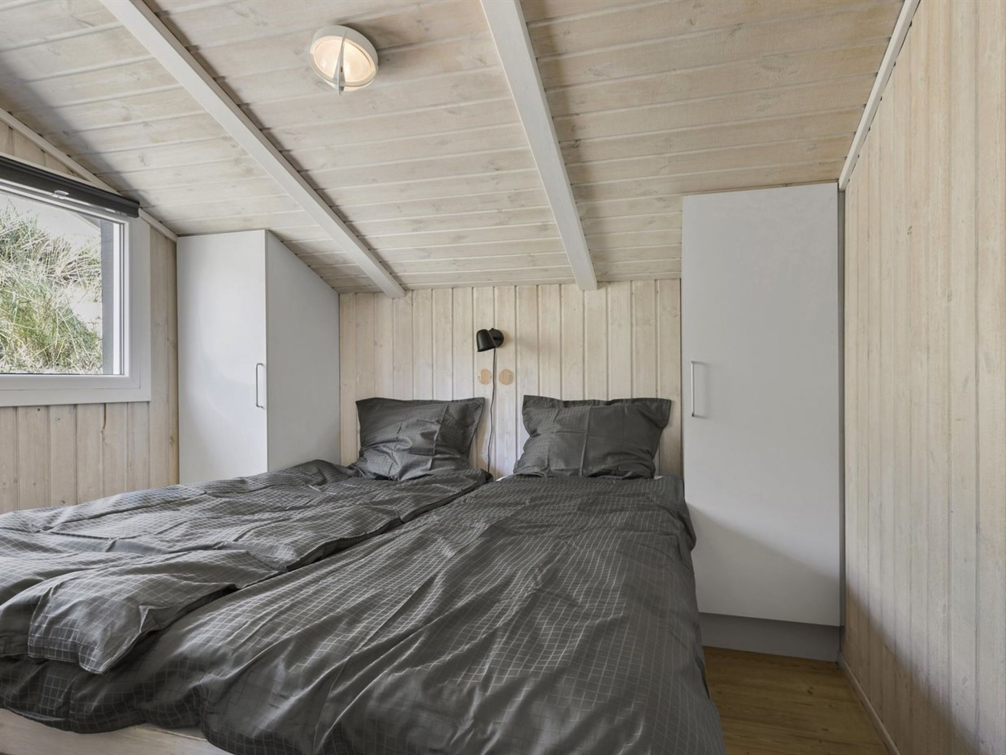 Ein Schlafzimmer mit Bett, Fenster und Deckenleuchte.