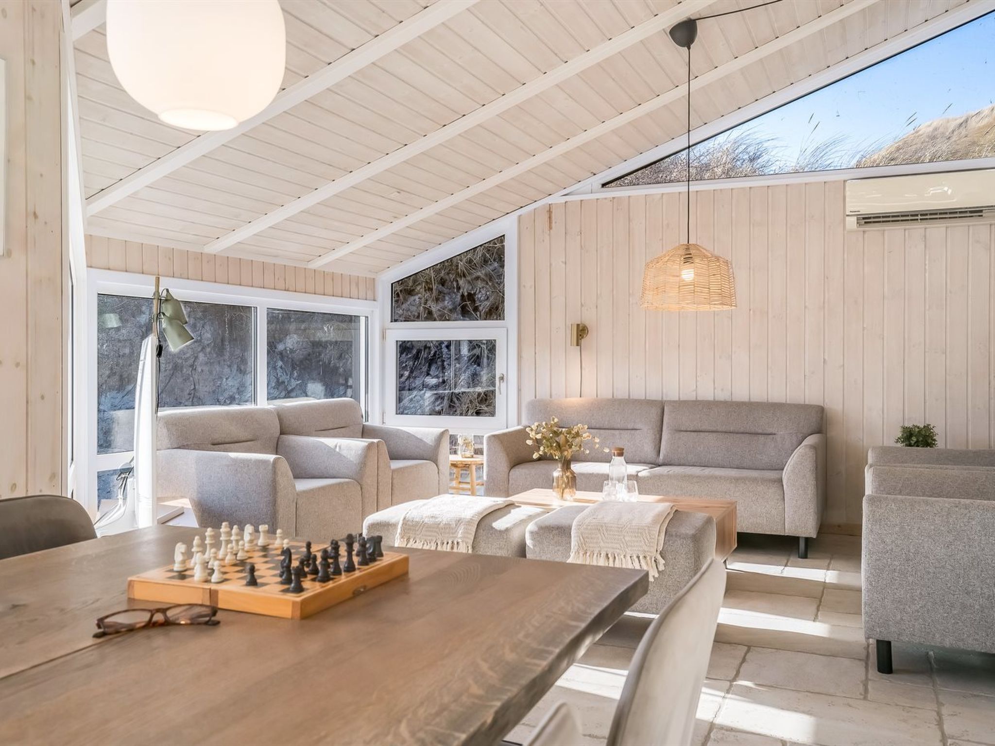 Un salon chaleureux avec un plafond en bois, un canapé, une table basse et un jeu d’échecs.