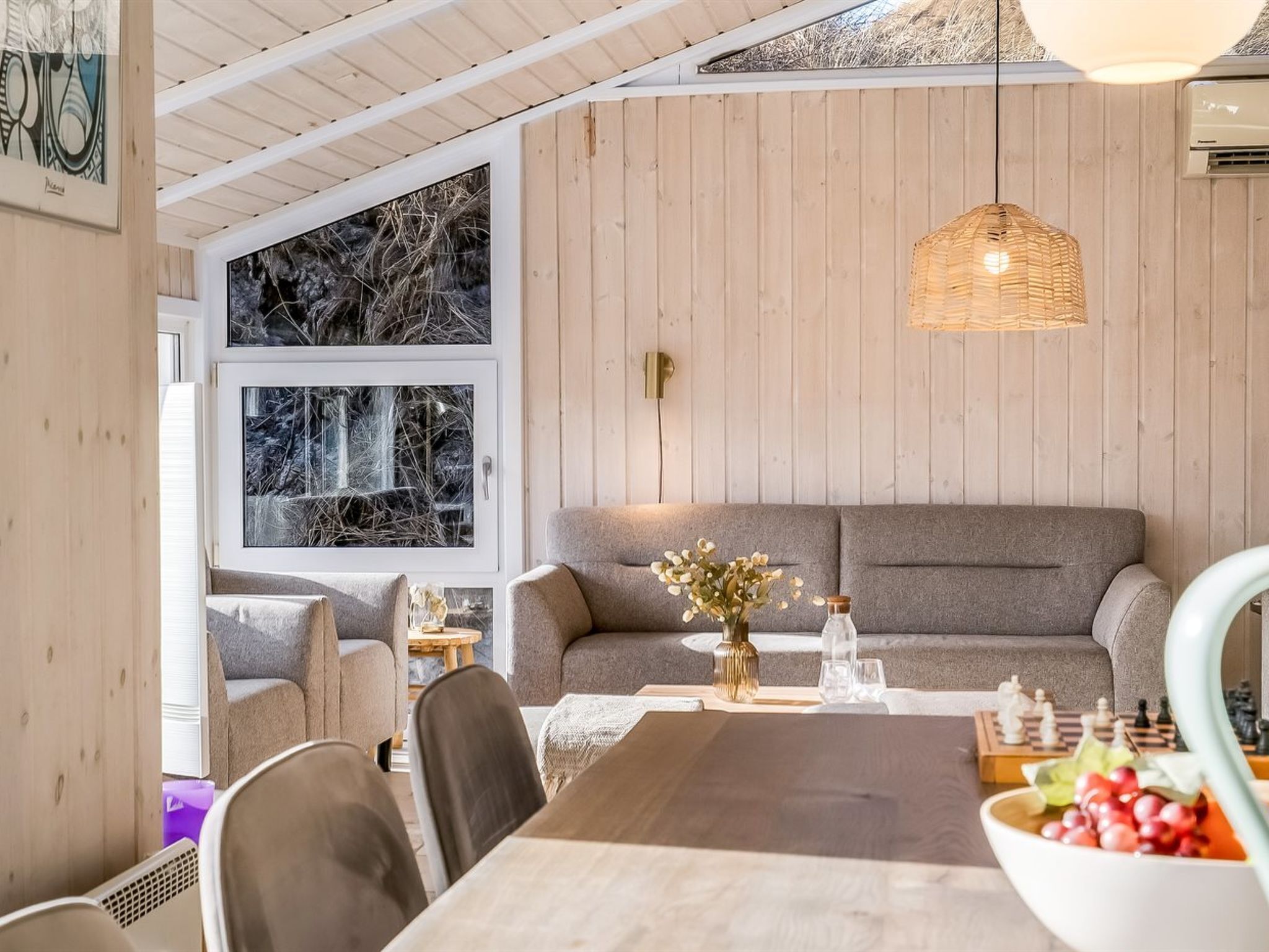 Una habitación acogedora con techo de madera, un sofá, una mesa de comedor con sillas y un tablero de ajedrez.