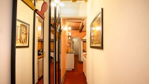 A narrow hallway with red-tiled flooring, leading to a kitchen area with white cabinets and a refrigerator. - Apartment Historical Center Florence (Firenze)