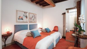 A bedroom with a bed, pillows, a nightstand, a mirror, and artwork on the wall. - Apartment Historical Center Florence (Firenze)