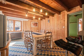 Ein Holzinterieur mit Schachbrettfußboden, einem Esstisch mit Stühlen und einer Bar.