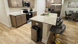 Eine moderne Küche mit Granit Arbeitsplatten, Edelstahlgeräten und einer Bar mit Hockern.