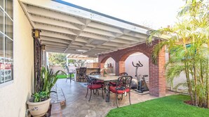 An outdoor patio with a covered dining area, a brick wall, and a small garden.