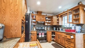 A kitchen with wooden cabinets, a refrigerator, an oven, and a microwave. There is a box of yogurt on the counter.