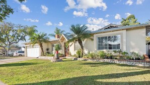 A residential house with a garage, a well-maintained lawn, and a variety of potted plants.