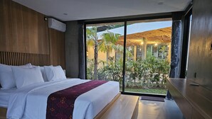 A modern hotel room with a large bed, a view of the garden, and a wooden ceiling. - Widji Garden Villa (Pecatu)