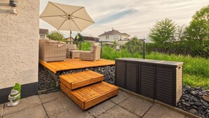 Une terrasse extérieure aménagée avec des meubles en osier, une table en bois et un grand parasol.