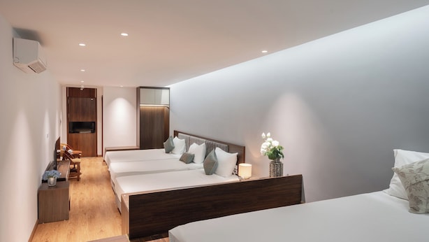 Een moderne hotelkamer met een houten vloer, een bed met een houten hoofdbord, een bureau, een stoel en een klein tafeltje met een plant.