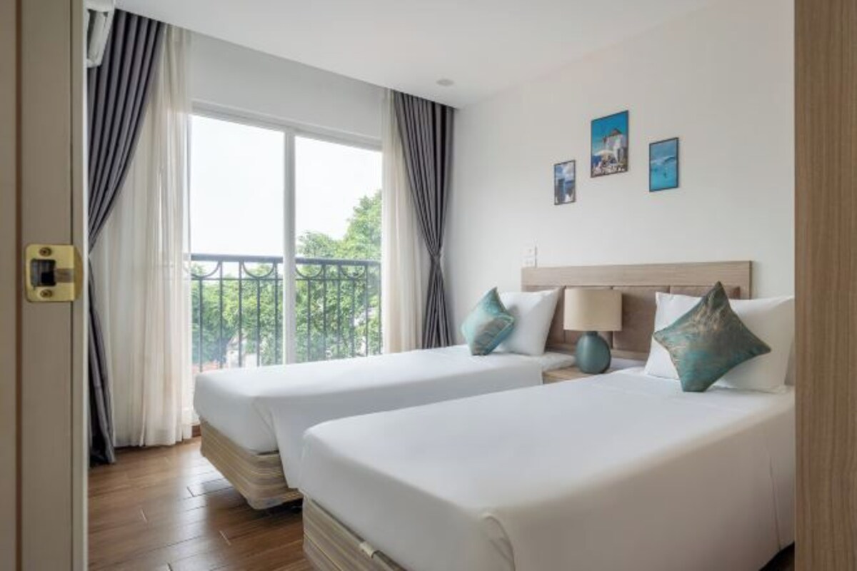 Habitación de hotel con dos camas, balcón y vistas a zonas verdes.