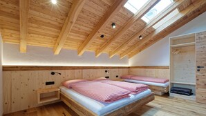 A wooden-paneled room with two beds, a skylight, and a wooden wardrobe. - Vacation apartment "Tischlerhof Alm" with balcony and mountain view (St.Jakob/Ahrntal)