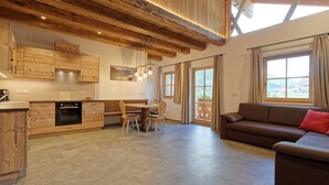 A modern kitchen with wooden cabinets and a dining area with a table and chairs. - Vacation apartment "Tischlerhof Alm" with balcony and mountain view (St.Jakob/Ahrntal)