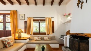 Uma sala de estar acolhedora com um sofá, uma mesa de centro com um livro, uma lareira e uma janela com cortinas.