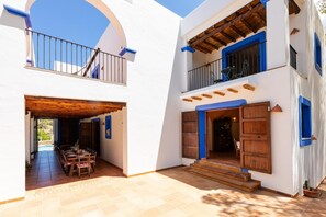 A two-story building with a patio area, wooden furniture, and a staircase leading to the upper floor. - Villa 'San Miguel Park' with Mountain View, Private Pool and Wi-Fi (Ibiza Town)