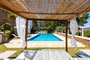 A pool area with a pergola, stone flooring, and white curtains. - Villa 'San Miguel Park' with Mountain View, Private Pool and Wi-Fi (Ibiza Town)
