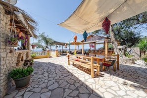 Eine terrasse mit Steinpflaster, Holzmöbeln und hängenden Laternen.