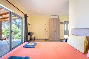 A bedroom with a bed, a desk, a wardrobe, and a view through a sliding door. - Studio Apartment 'With Sea View 1' with Sea View, Wi-Fi and Air Conditioning (Corfu)