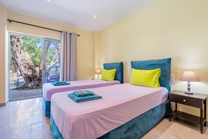 A hotel room with two beds, a nightstand, a lamp, and a view of a tree through a glass door. - Studio Apartment 'Rolling Stone 3' with Wi-Fi and Air Conditioning (Corfu)