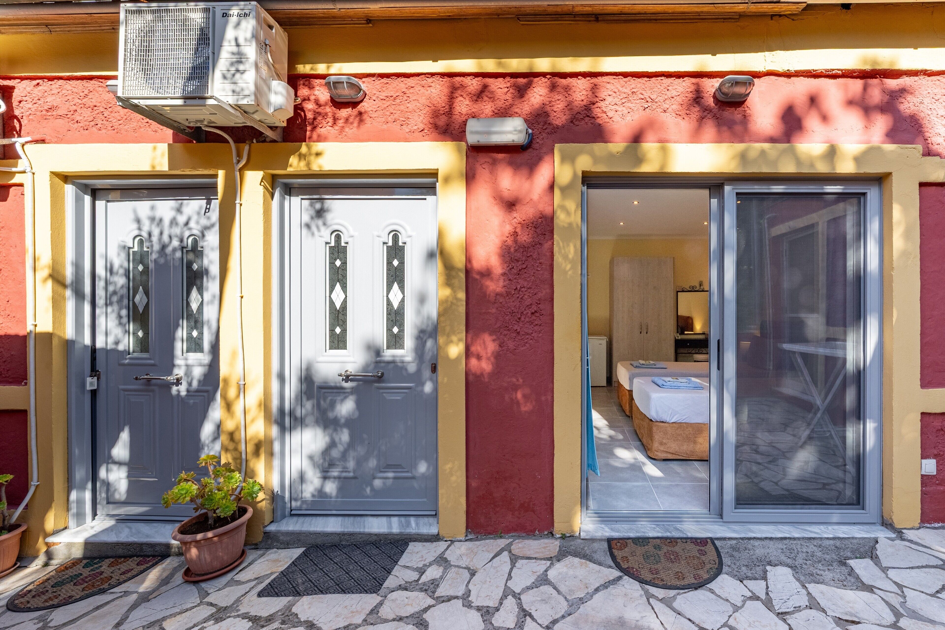Un bâtiment avec deux portes, un pot de fleurs et une entrée pavée de pierres.