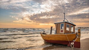 Ein hölzernes Boot mit Kabine und Mast, an der Küste mit einem Seil festgemacht.
