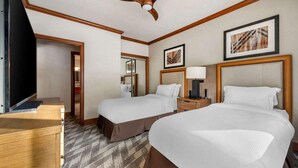 A hotel room with two beds, a desk, a television, and artwork on the walls. - 2 Bedroom at Valdoro Mountain Lodge, a Hilton Grand Vacations Club (Breckenridge)