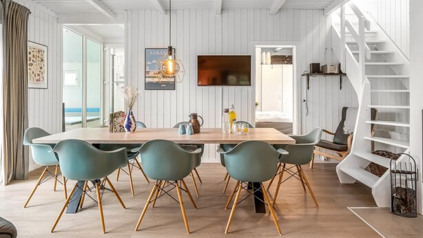A modern dining area with a wooden table, teal chairs, and a hanging light fixture. - "Caya" - 750m from the sea by Interhome (Løkken)