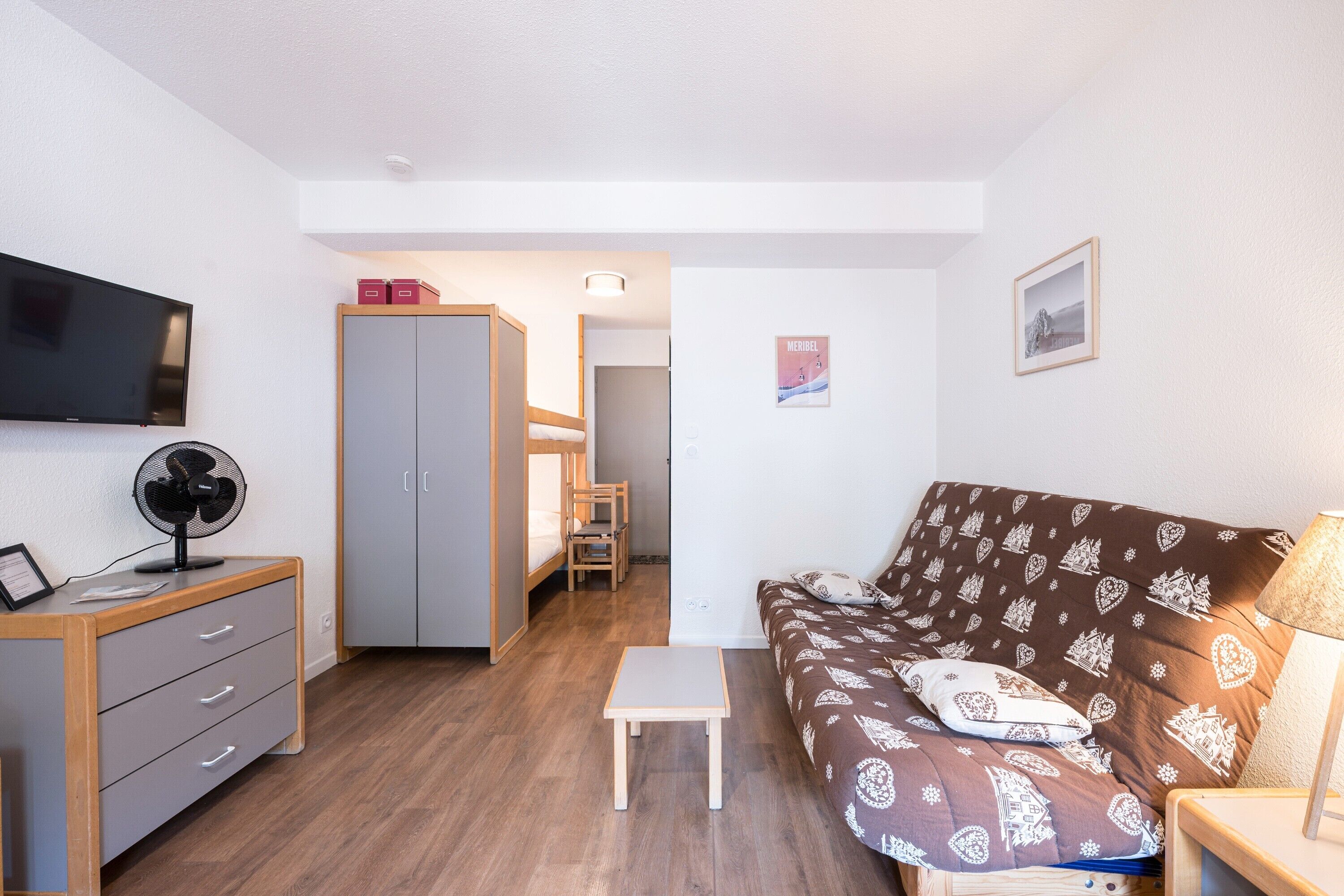A room with a bed, a desk, a chair, a TV, and a wardrobe.