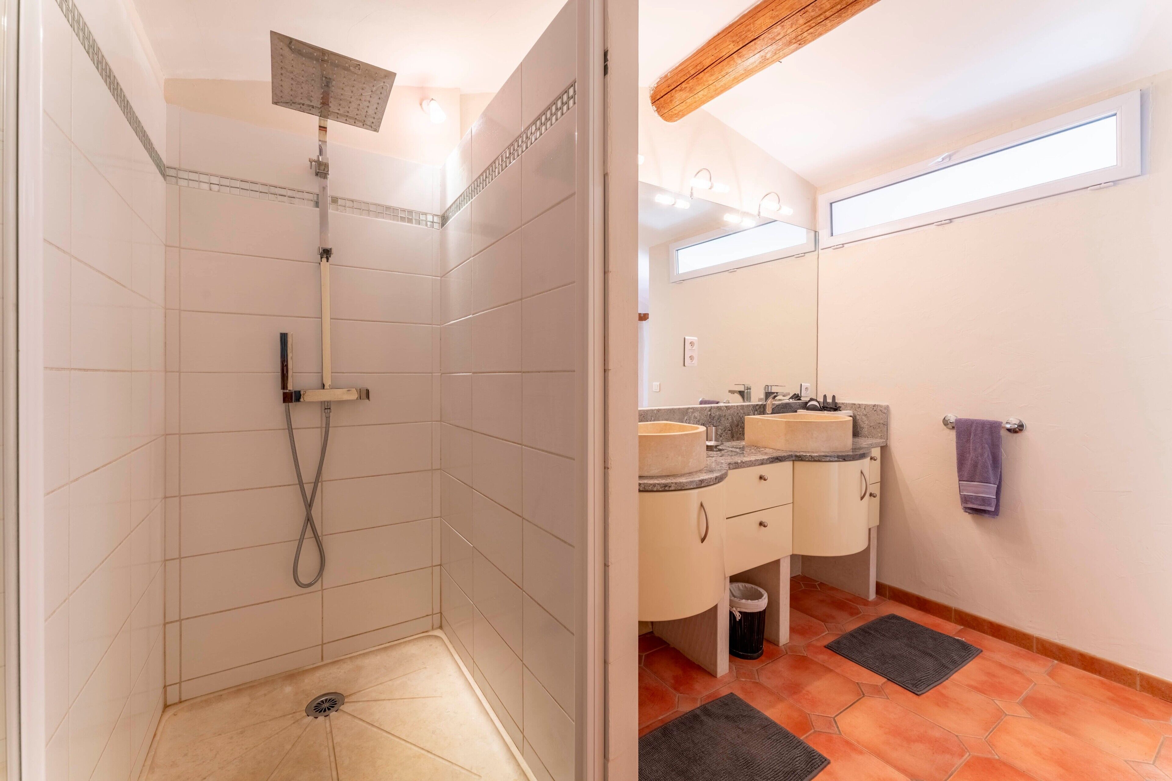 Une salle de bain avec une douche, deux lavabos, un miroir et un porte-serviettes.