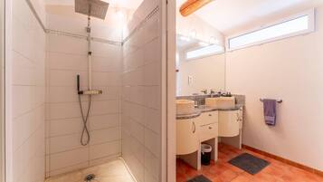 Une salle de bain avec une douche, deux lavabos, un miroir et un porte-serviettes.
